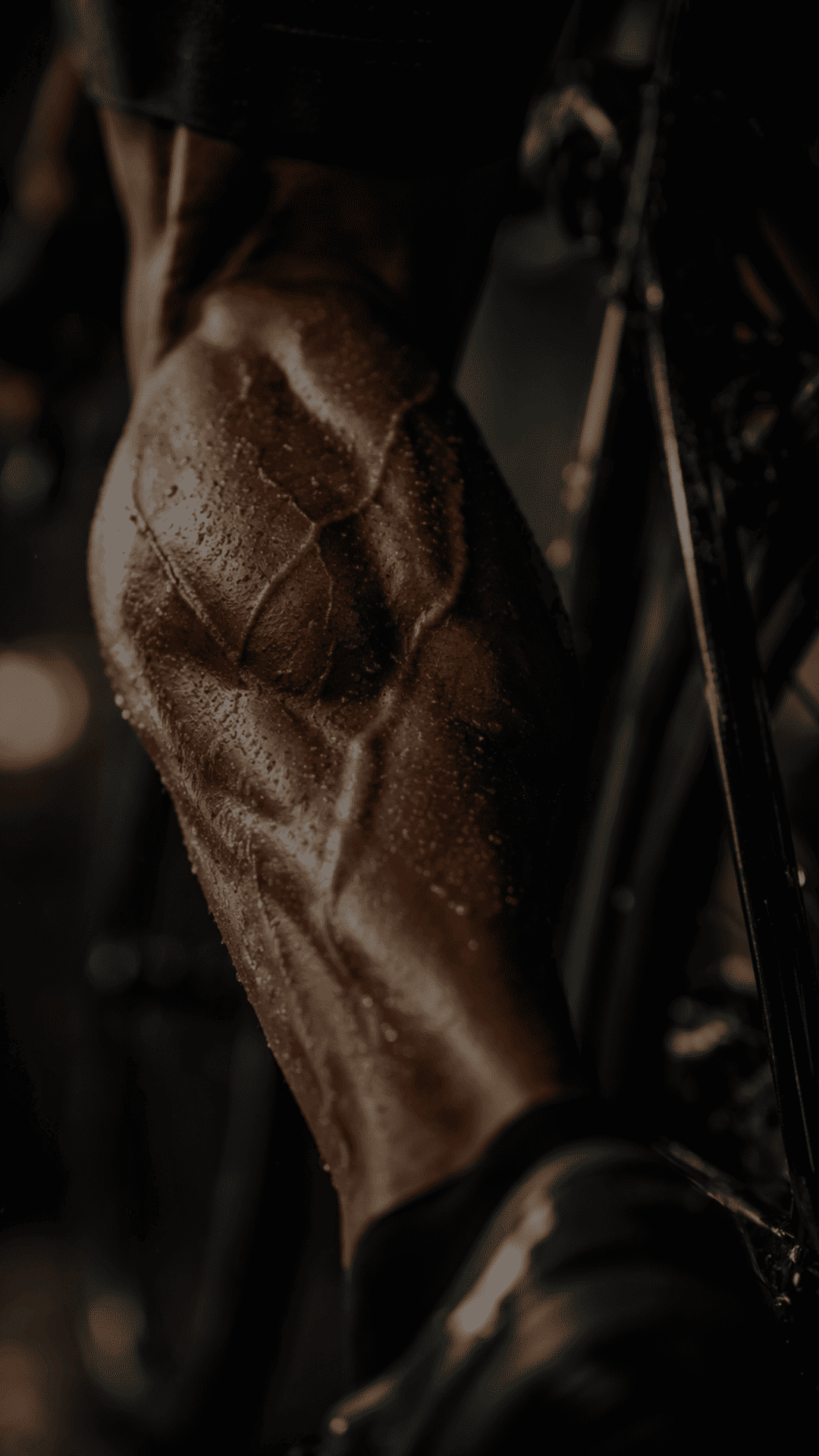 Close-up detalhado da musculatura da perna de um ciclista suado em ambiente escuro e dramático.