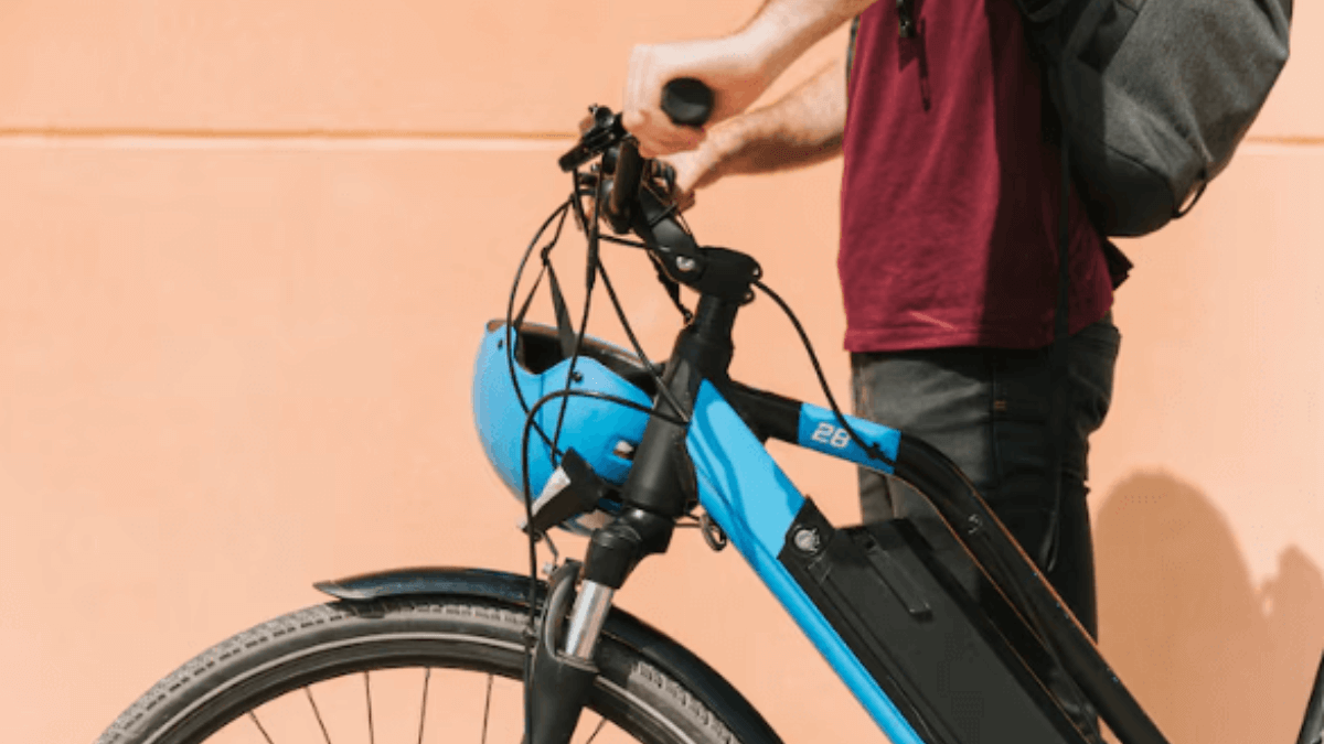 Pessoa segurando bicicleta elétrica urbana com bateria integrada no quadro, ideal para deslocamentos diários na cidade